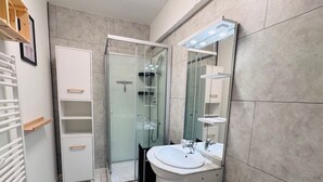 Ein modernes Badezimmer mit Duschkabine aus Glas, einem weißen Waschbecken und einer Toilette.