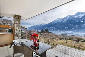 Ein Balkon mit Tisch, Stühlen, einer Weinflasche und einem Blumenstrauß.