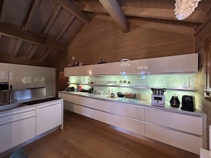 A modern kitchen with white cabinetry, a wooden ceiling, and a countertop with various appliances and glassware. - Spacious 5-room apartment for 8 people in Méribel with private parking (Méribel)