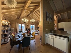 A spacious dining area with a high ceiling and wooden beams, a kitchen with white cabinets, and a view of the outdoors. - Spacious 5-room apartment for 8 people in Méribel with private parking (Méribel)
