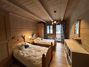 A cabin-style room with two wooden beds, a small desk, and a window with curtains. - Spacious 5-room apartment for 8 people in Méribel with private parking (Méribel)