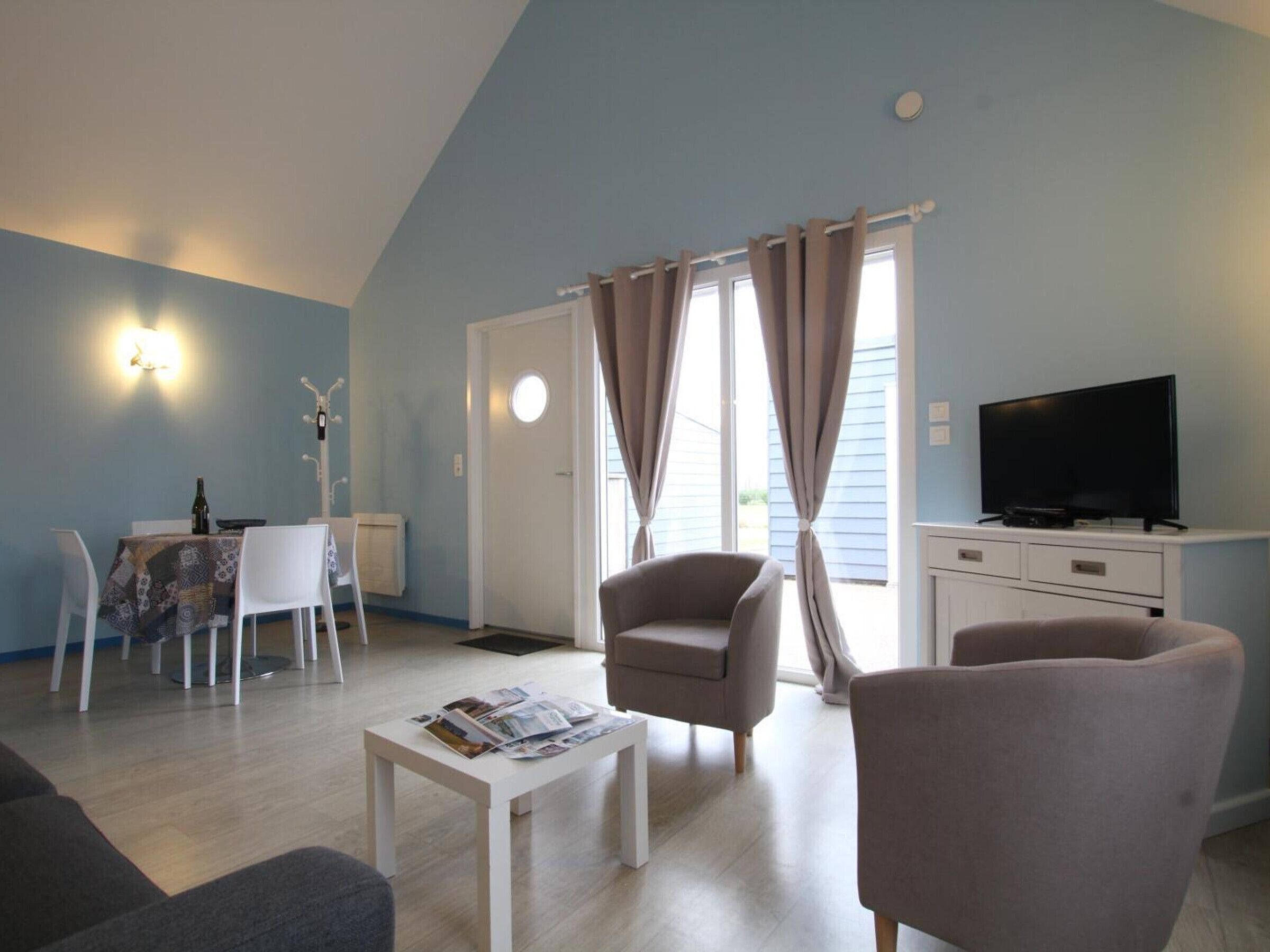 A living room with a sofa, armchairs, a coffee table, a TV, and a dining area with a table and chairs.