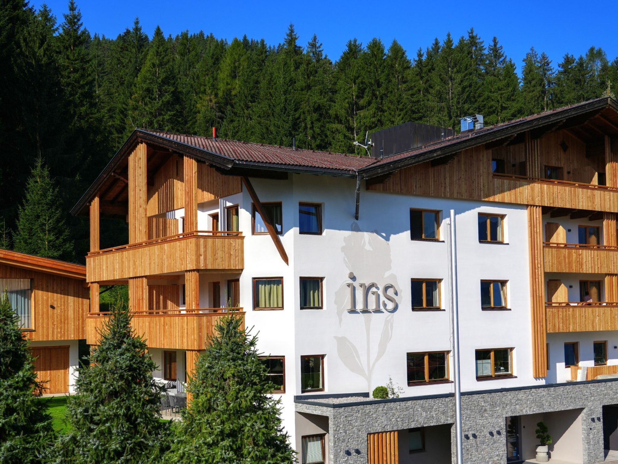 Et hotel med flere etager, træbalkoner og et bjerg i baggrunden.