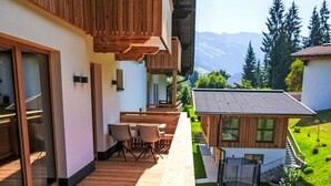Un edificio moderno con balconi in legno, una sala da pranzo con sedie e vista sulle montagne.