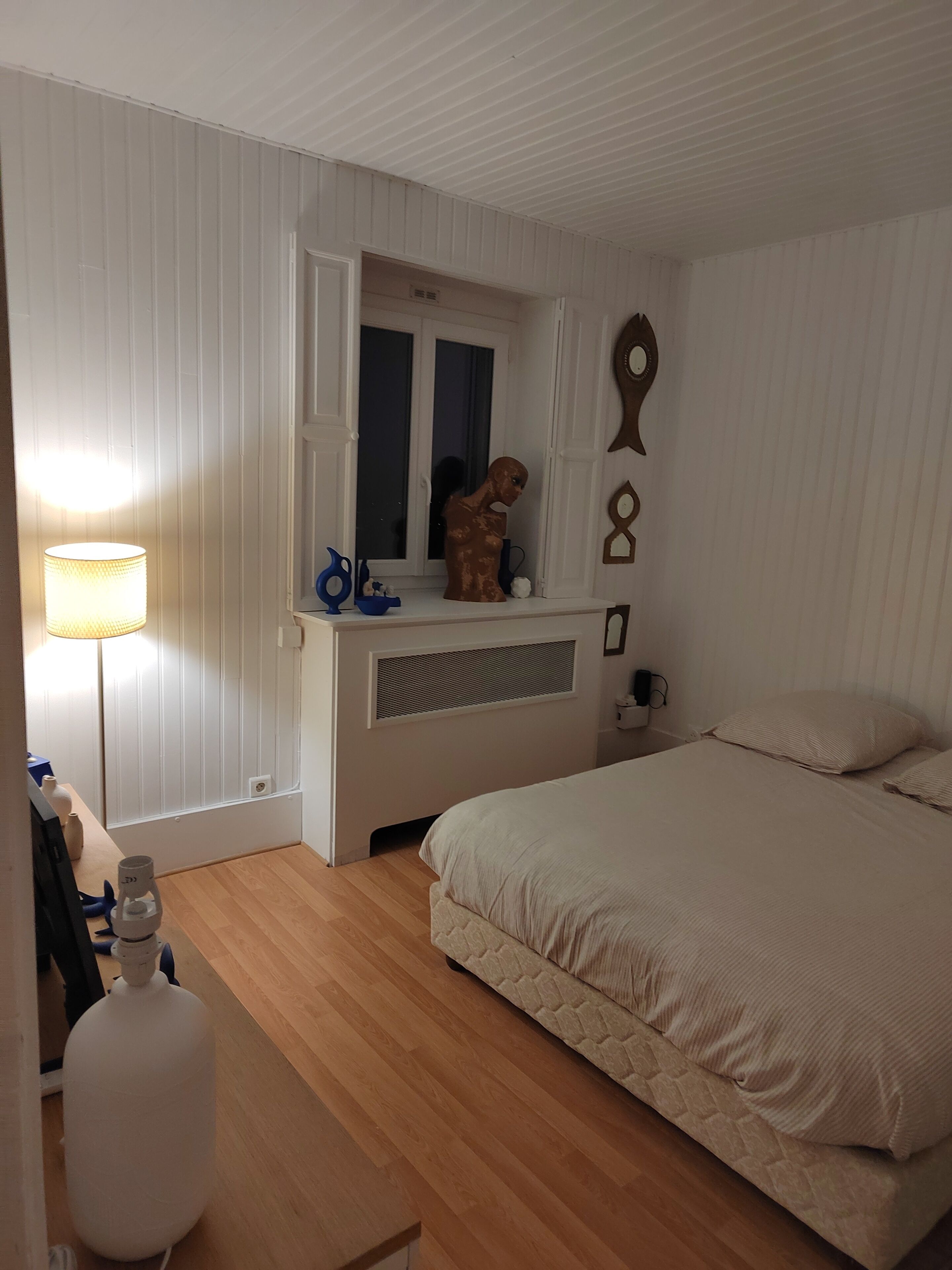 A bedroom with a bed, a dresser, a mirror, and a lamp.