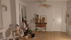 A room with a wooden floor, a wicker chair, a small table with a sculpture, and a hanging light fixture. - A cocoon of calm and serenity in the heart of Saint-Florentin (Saint-Florentin)
