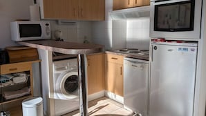 Una cucina compatta con microonde, fornello, forno e lavatrice.