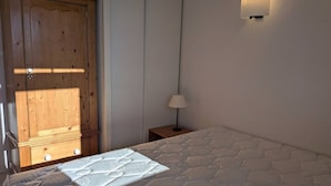 Camera da letto con un letto, un armadio in legno, un comodino con una lampada e una lampada a parete.