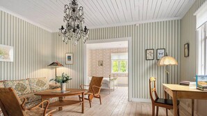 A room with striped wallpaper, a chandelier, a sofa, chairs, a table, and a lamp.