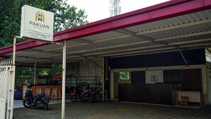 A covered parking area with motorcycles and a sign for Pakuan Residence. - Pakuan Residence Hotel (Bogor)