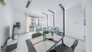 Una sala de estar moderna con una mesa de comedor, sofás y un ventanal grande.