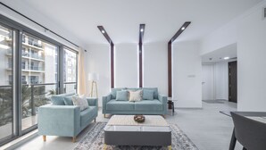 Una sala de estar moderna con un ventanal grande, un conjunto de sofá, una mesa de centro y una alfombra estampada.