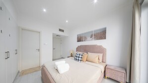 Un dormitorio moderno con una cama grande, mesitas de noche, un armario y un cuadro en la pared.