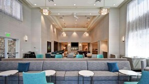 Eine großzügige Lobby mit einer zentralen Sitzecke, einer Bar und einem Fernsehbildschirm.