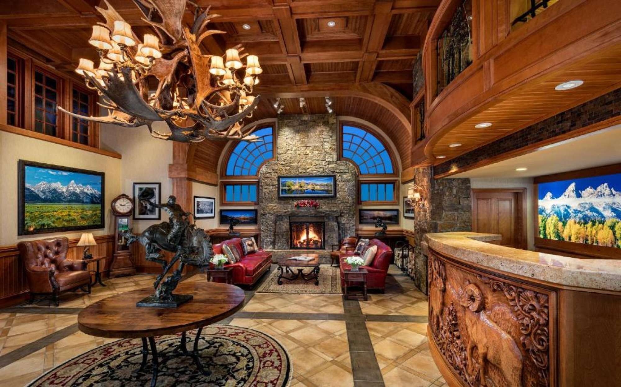 A spacious lobby with a fireplace, wooden ceiling, and a large chandelier.