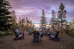 Zona salotto con poltrone Adirondack rivolta verso un panorama di alberi e un specchio d'acqua.