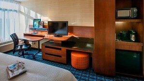 Habitación de hotel con escritorio de madera, televisor, microondas y minibar.