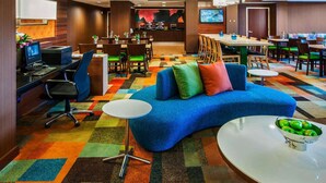 Un vestíbulo de hotel moderno con un sofá azul, una estación de café y una pantalla de televisión.
