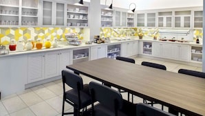 Une cuisine moderne avec des meubles blancs, un îlot central doté de sièges et un revêtement mural à motifs géométriques.