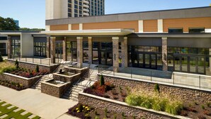 A modern hotel with a covered entrance, stone pillars, and a landscaped courtyard.