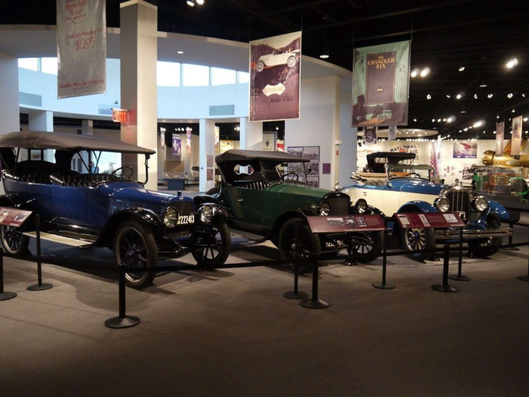 A museum exhibit with vintage cars on display.