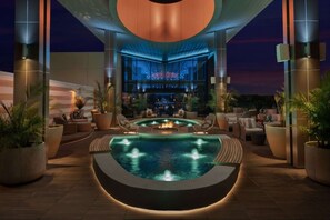 A pool area with a fire feature, seating, and a bar in the background. - Next to Gas South Arena + Rooftop Bar. Pool. Gym. (Duluth)