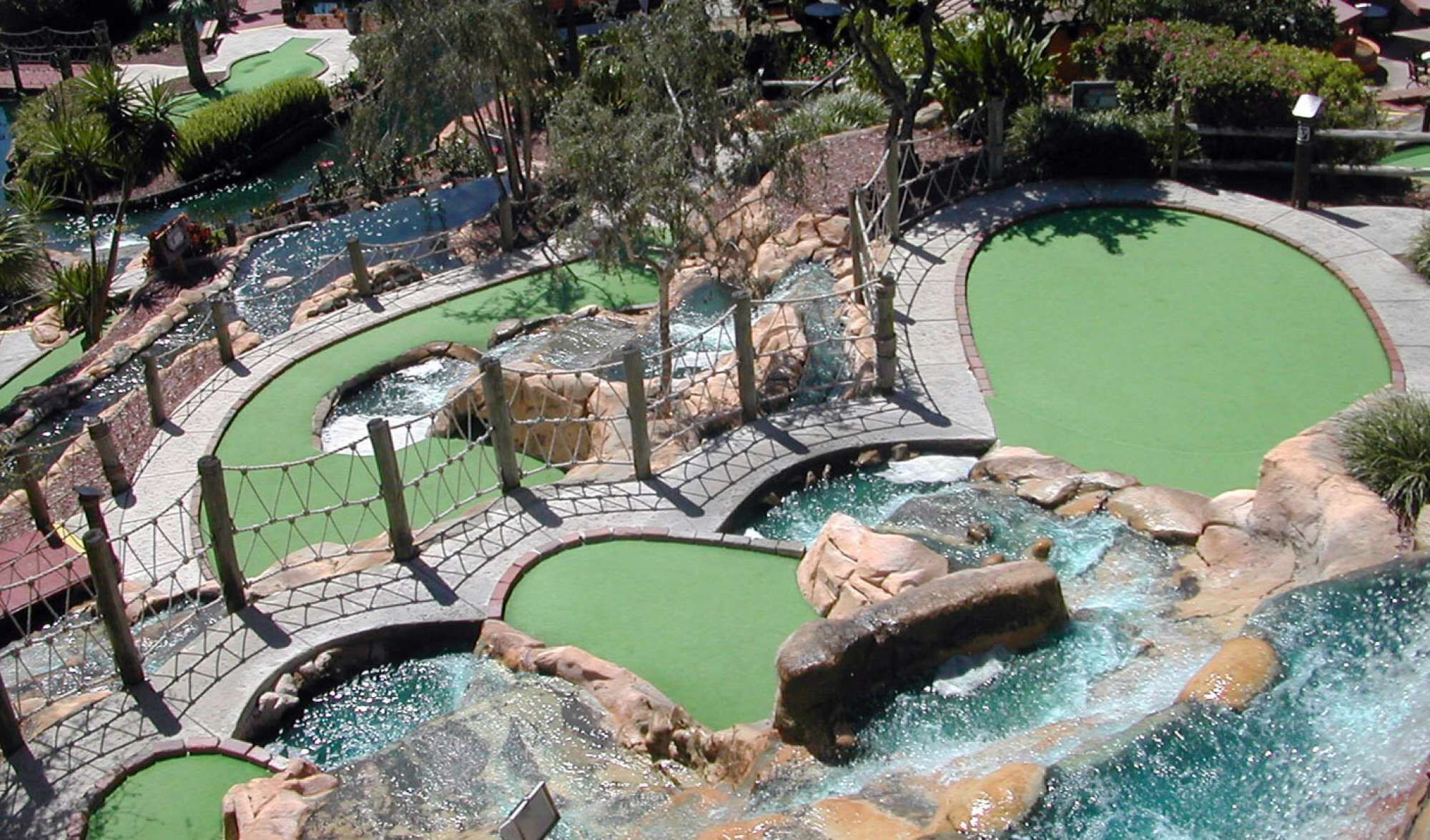 A golf course with multiple putting greens, water features, and a bridge.