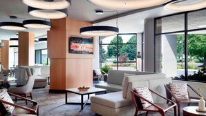 A modern hotel lobby with a seating area, large windows, and a sports-themed wall art. - Steps from University of Dayton + Restaurant&Pool (dayton)