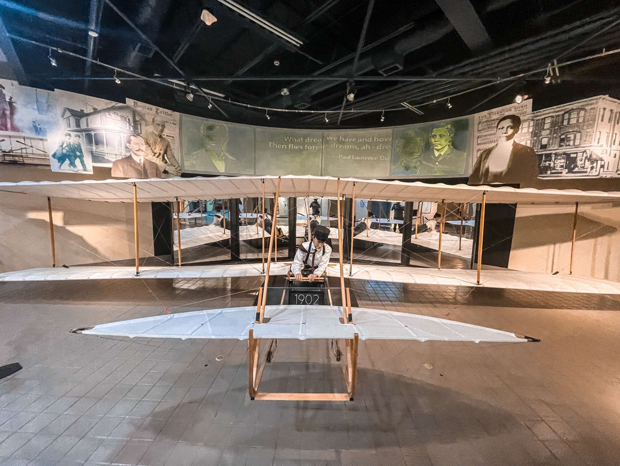 An exhibition with a central display of a vintage aircraft model, surrounded by informational panels and artwork.