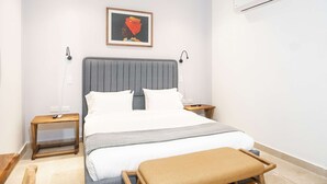 A bedroom with a bed, bedside tables, a nightstand, a bench, an air conditioner, and a framed picture on the wall. - w Designer Loft in the Heart of Bocagrande (Cartagena)