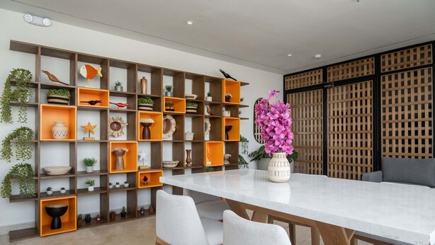 A modern dining area with a white table, grey chairs, and a wooden wall with shelves containing various decorative items. - w Designer Loft in the Heart of Bocagrande (Cartagena)