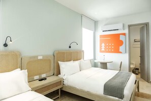 A hotel room with two beds, a small table, and a wall-mounted air conditioning unit. - w Luxe Urban Loft in the Heart of Bocagrande (Cartagena)