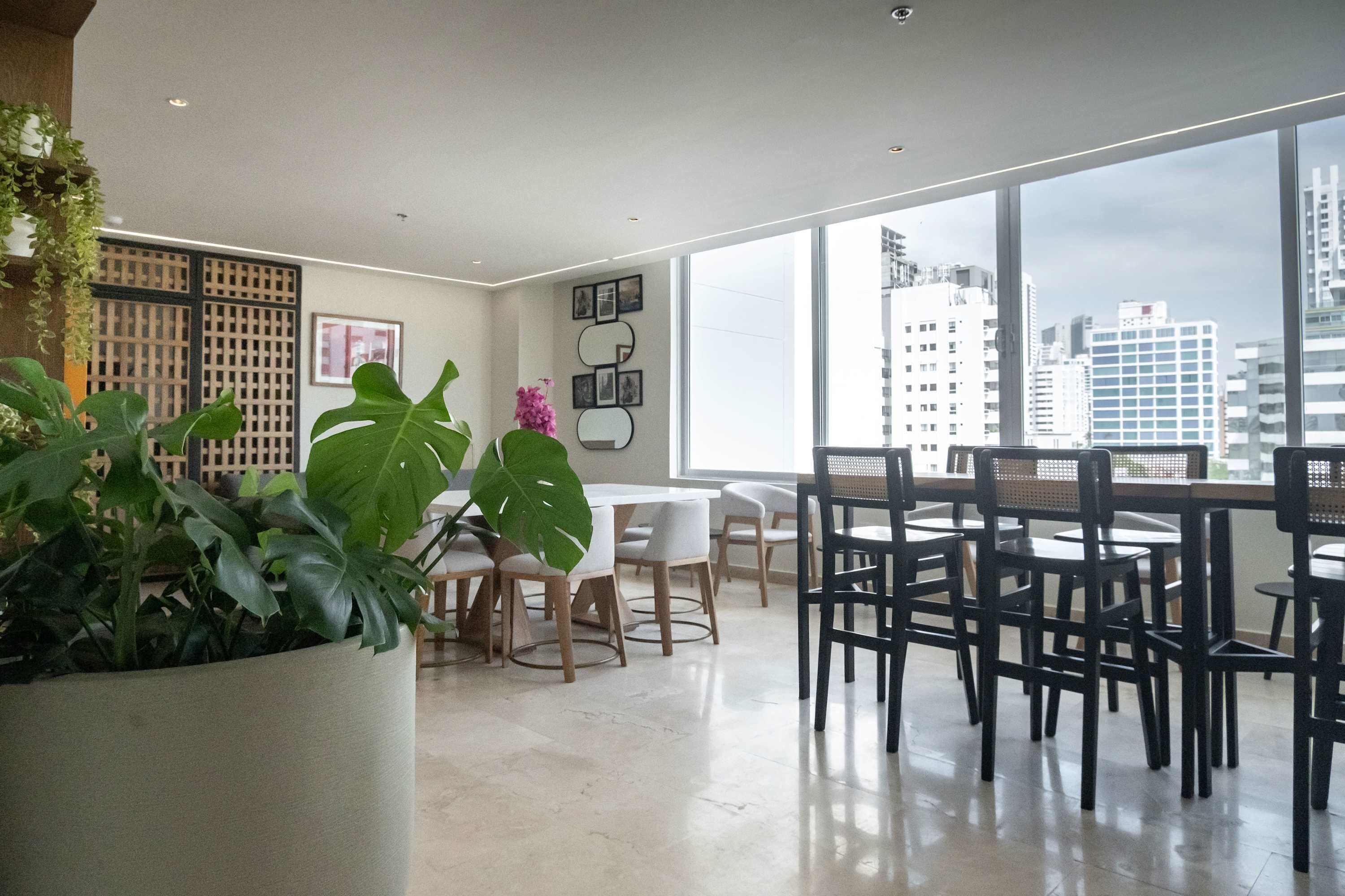 A modern dining area with a large window, a white table, and black chairs.