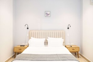 Ein Hotelzimmer mit einem Bett, zwei Nachttischen, einer Wandleuchte und einem kleinen Bild in einem Rahmen.