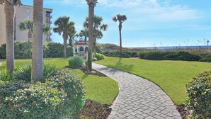 A landscaped pathway leading to a building with a red roof and a white fence. - Waters Edge 115 ~ Ground Floor ~ Beach Boardwalk Right Outside Your Door! (Fort Walton Beach)