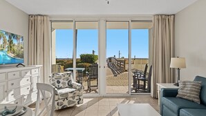 A hotel room with a balcony, a television, a dining area, and a sofa. - Waters Edge 115 ~ Ground Floor ~ Beach Boardwalk Right Outside Your Door! (Fort Walton Beach)