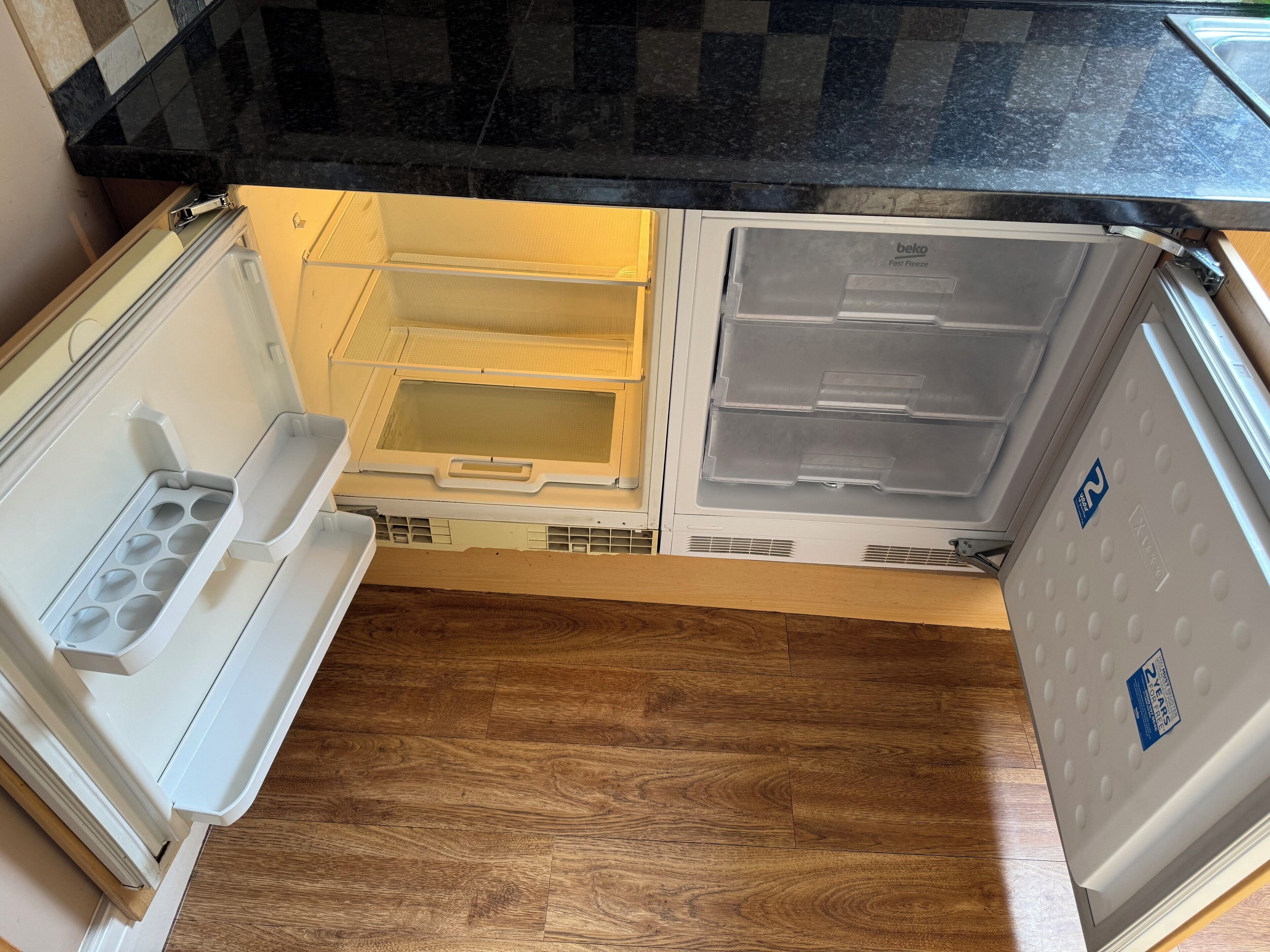 Een open koelkast met twee plateaus en een vriesvak.