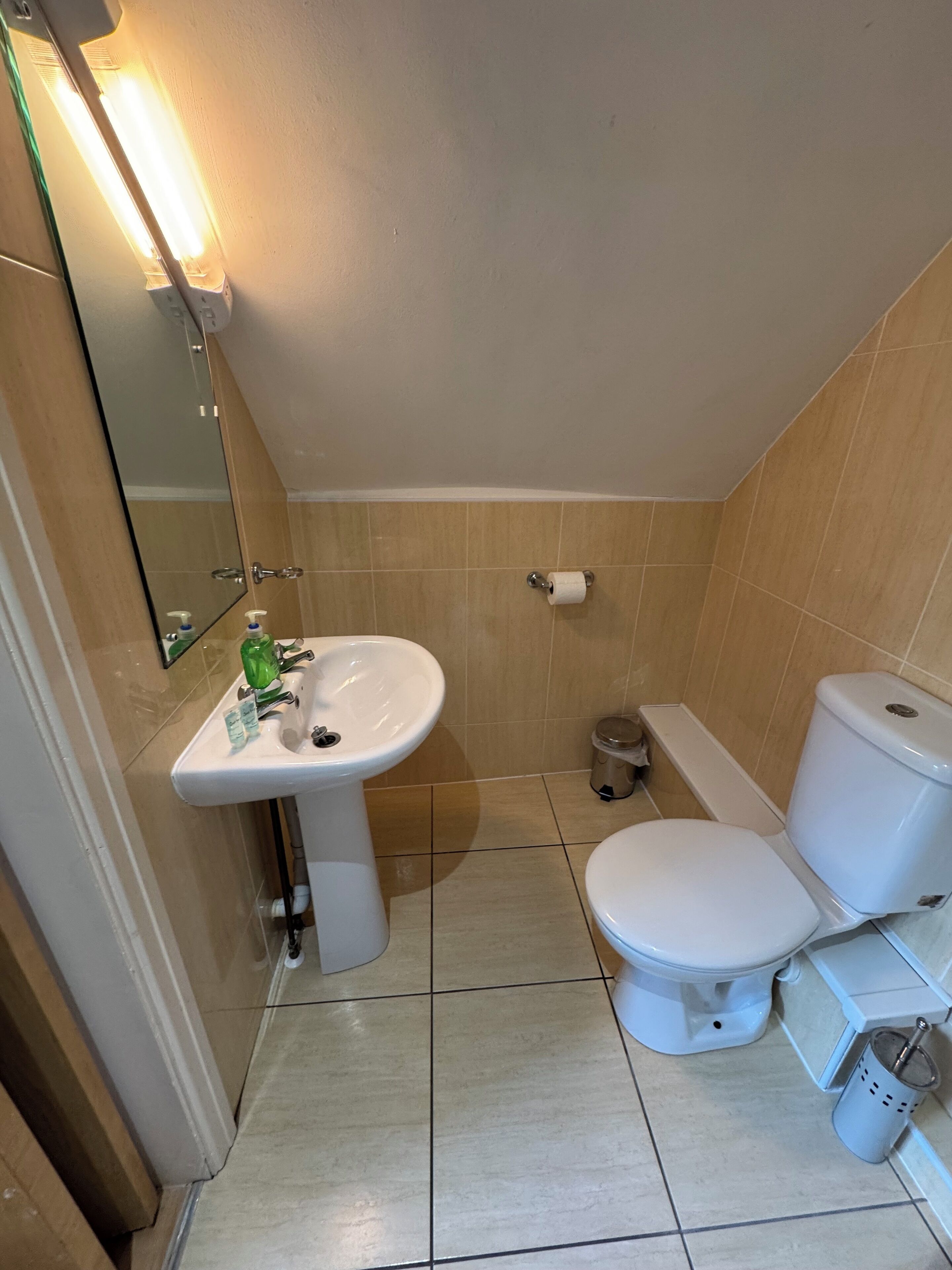 Ein kleines Badezimmer mit Waschbecken, Toilette und Spiegel, alles in Weiß.