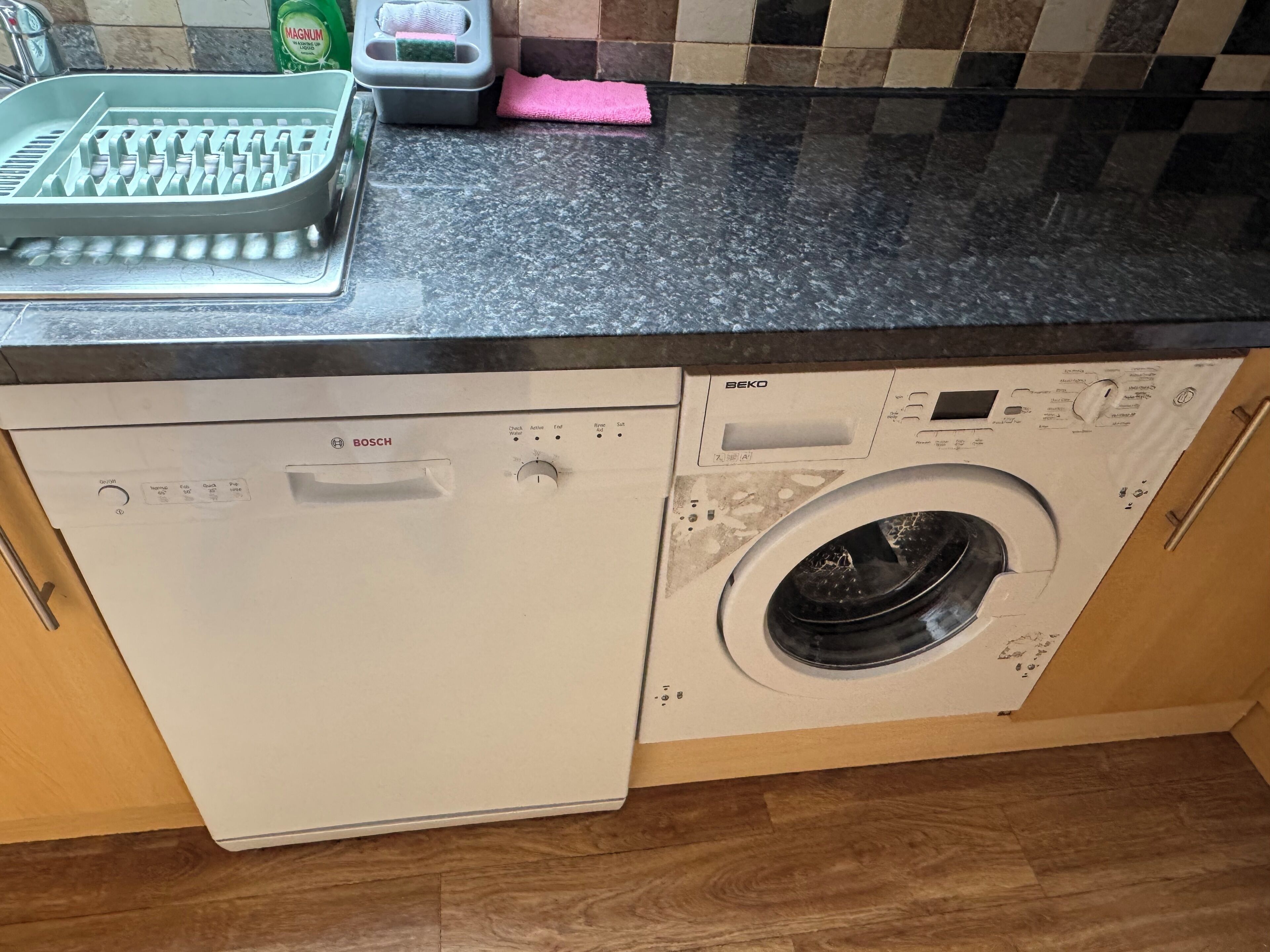 A compact kitchen with a Bosch dishwasher and a front-loading washing machine.