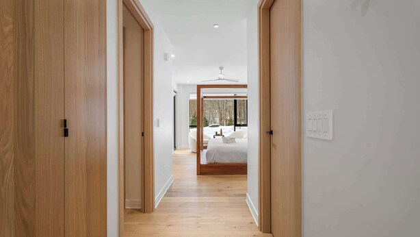 Ein Flur, der in ein Schlafzimmer mit Bett, Deckenventilator und Blick ins Freie führt.