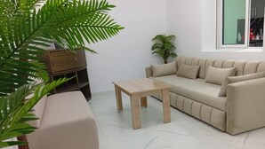 Una sala de estar con un sofá color crema, una mesa de centro de madera y una planta en maceta.