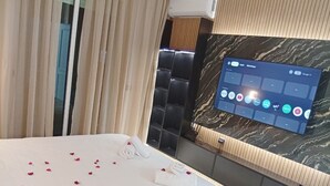 Habitación de hotel con una cama, un televisor montado en la pared y una ventana con cortinas.