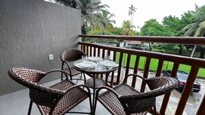 A balcony with wicker furniture, a table set for four, and a view of a green landscape with palm trees. - Atlantico Praia dos Carneiros - Proximo da Igrejinha (Tamandaré)
