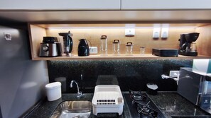 A compact kitchen with a sink, stove, and various appliances like a coffee maker and kettle. - Atlantico Praia dos Carneiros - Proximo da Igrejinha (Tamandaré)
