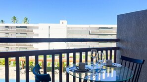 A balcony with a glass table set for two, a chair, and a view of modern buildings. - Atlantico Praia dos Carneiros - Proximo da Igrejinha (Tamandaré)
