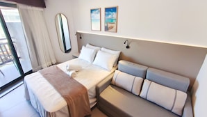 A hotel room with a bed, a sofa, a window with curtains, a wall-mounted mirror, and two framed pictures. - Atlantico Praia dos Carneiros - Proximo da Igrejinha (Tamandaré)