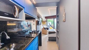 Eine moderne Küche mit Einbauherd, Spüle und einer Essecke inklusive Sofa und Fernseher.