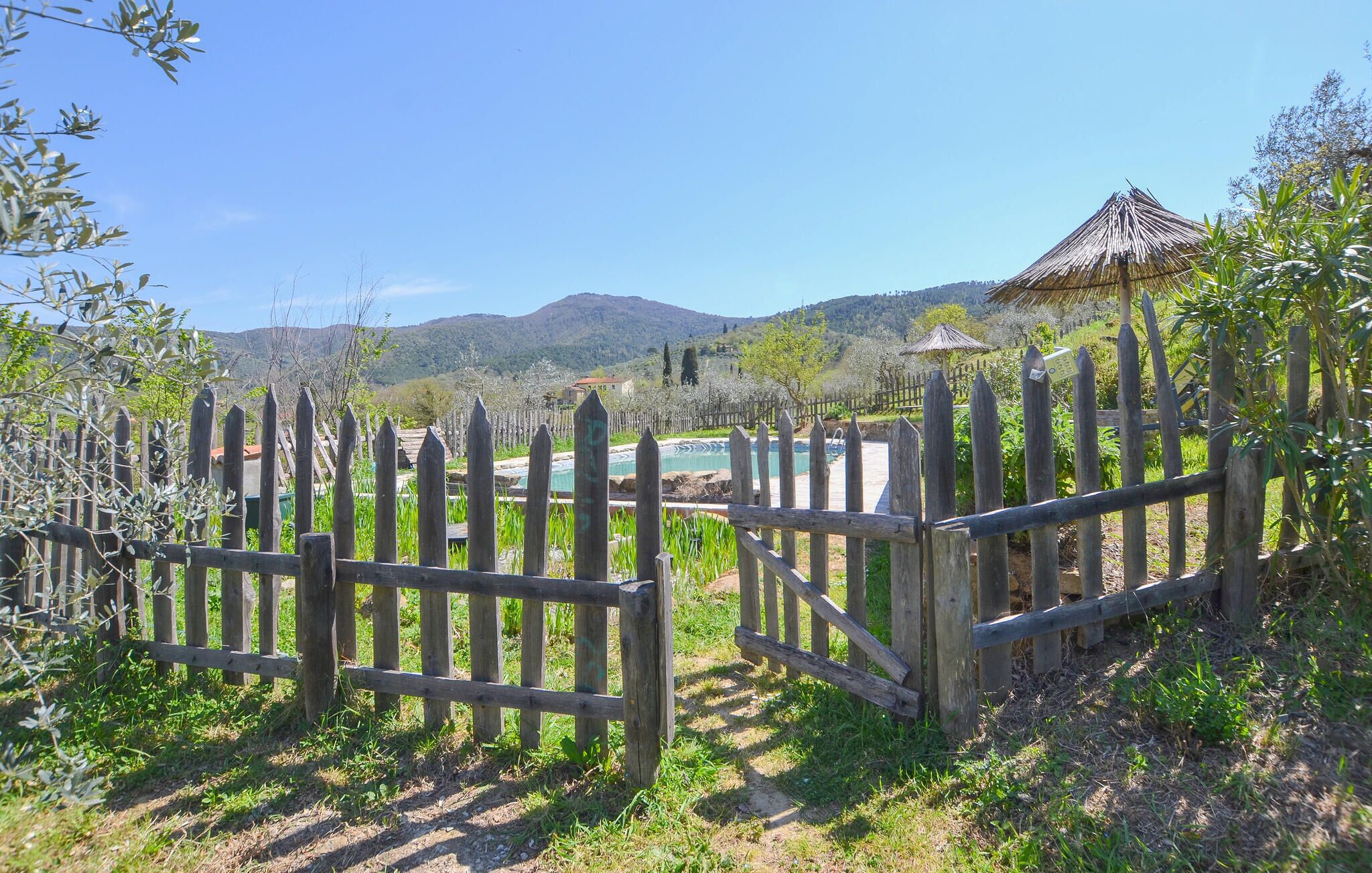 Uma vedação de madeira, uma piscina e uma paisagem montanhosa.