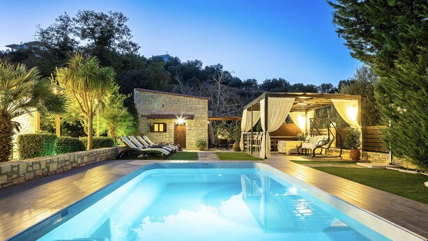 A swimming pool with a stone house and a covered outdoor seating area. - Maratho Villa - With Private Pool (Rethymno)