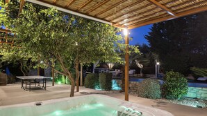 An outdoor hot tub area with a pergola overhead, surrounded by trees and a swimming pool. - Maratho Villa - With Private Pool (Rethymno)